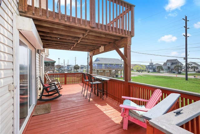 wooden deck with exterior bar and a lawn