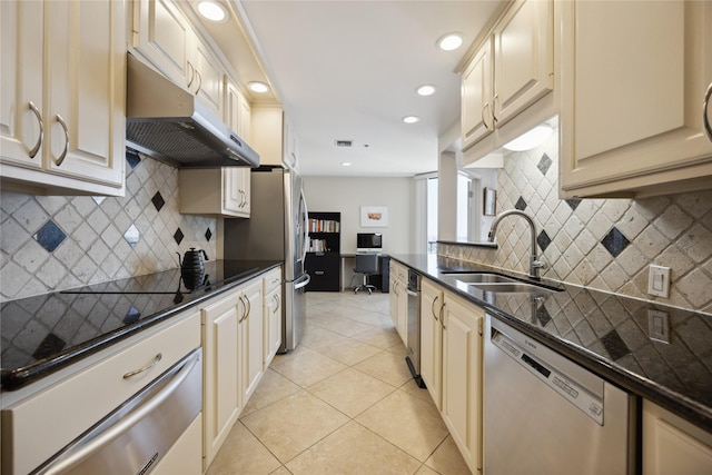 kitchen with sink, dark stone counters, light tile patterned floors, stainless steel appliances, and backsplash