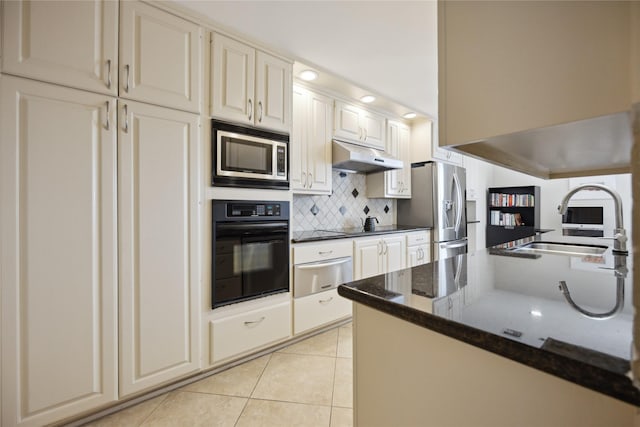 kitchen with light tile patterned flooring, sink, tasteful backsplash, dark stone countertops, and appliances with stainless steel finishes