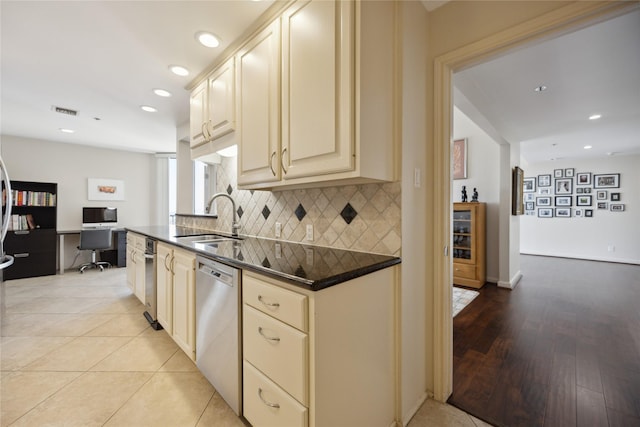 kitchen featuring stainless steel dishwasher, cream cabinets, sink, and backsplash