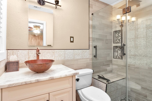 bathroom featuring vanity, a shower with door, and tile walls