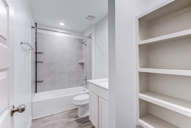 full bathroom featuring vanity, tiled shower / bath combo, toilet, and hardwood / wood-style flooring