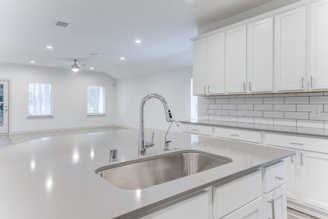 kitchen with lofted ceiling, sink, white cabinetry, ceiling fan, and decorative backsplash