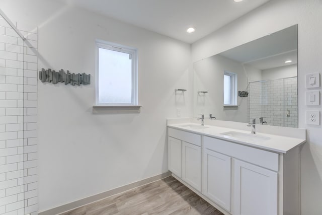 bathroom with wood-type flooring, tiled shower, and vanity