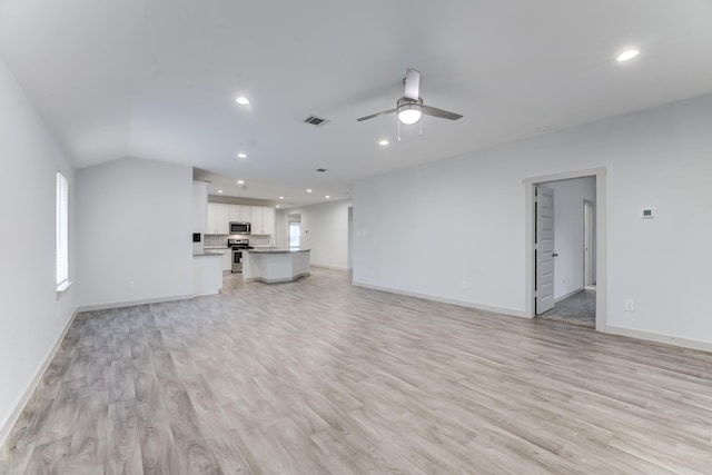 unfurnished living room featuring ceiling fan, vaulted ceiling, and light hardwood / wood-style floors