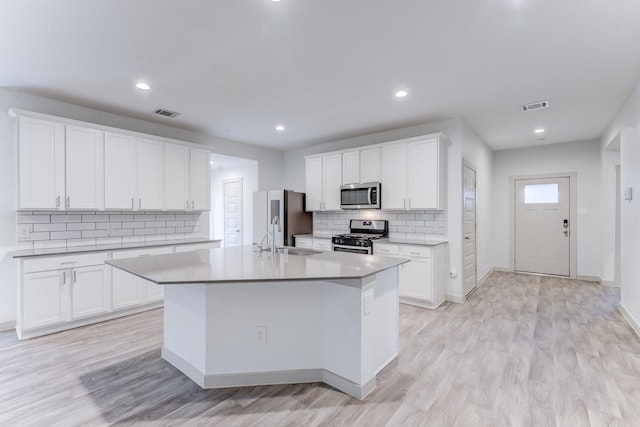 kitchen featuring an island with sink, appliances with stainless steel finishes, and white cabinets