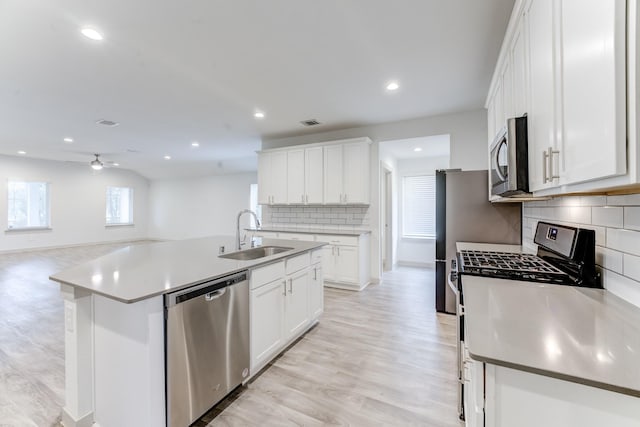 kitchen featuring sink, white cabinetry, a center island with sink, light wood-type flooring, and stainless steel appliances