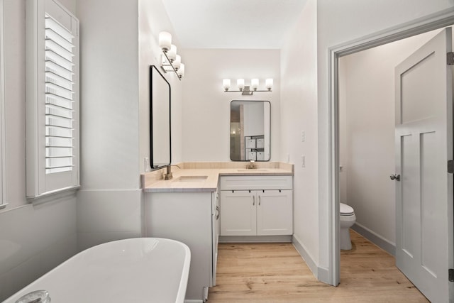 bathroom with hardwood / wood-style floors, vanity, a washtub, and toilet