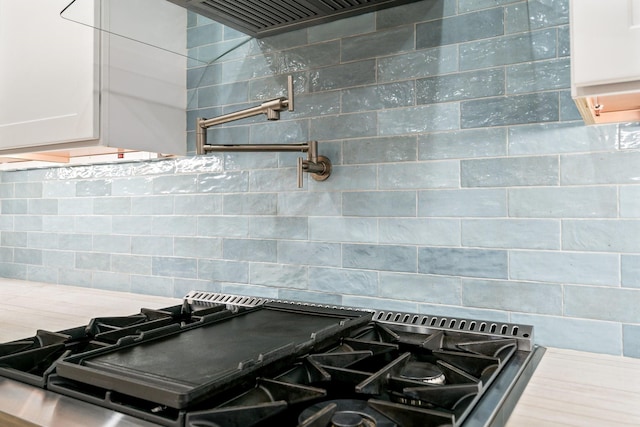 details featuring white cabinetry, backsplash, and gas stove