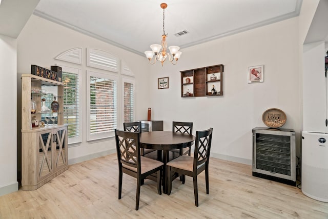 dining area featuring crown molding, beverage cooler, a chandelier, and light wood-type flooring