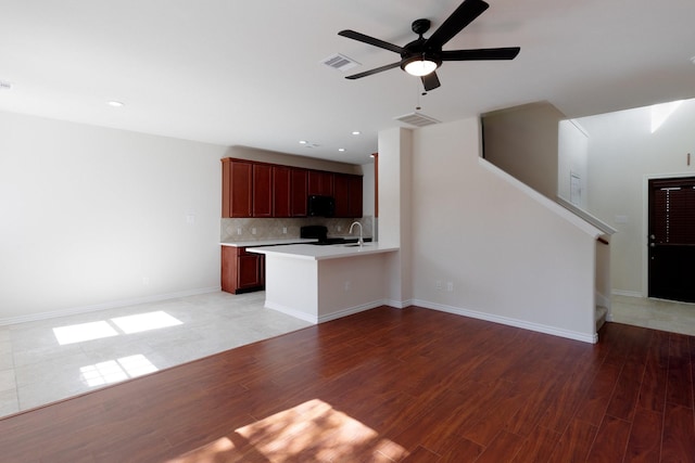 kitchen with wood-type flooring, sink, decorative backsplash, and kitchen peninsula