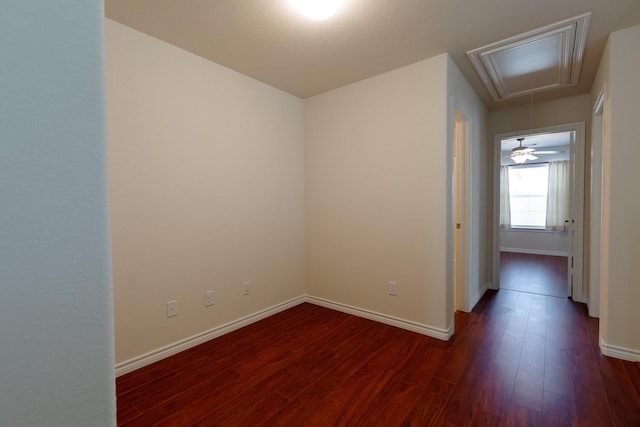 unfurnished room featuring attic access, baseboards, and wood finished floors