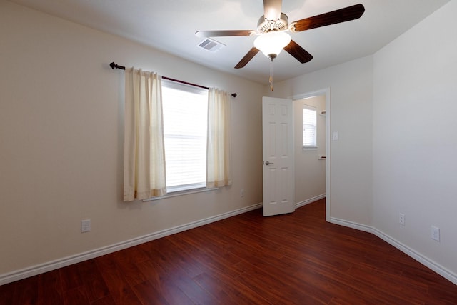 empty room featuring visible vents, a ceiling fan, dark wood-type flooring, and baseboards