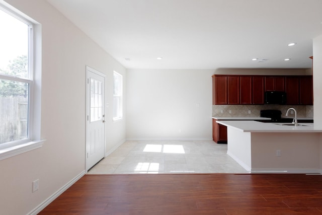 kitchen with a wealth of natural light, tasteful backsplash, black microwave, and a sink