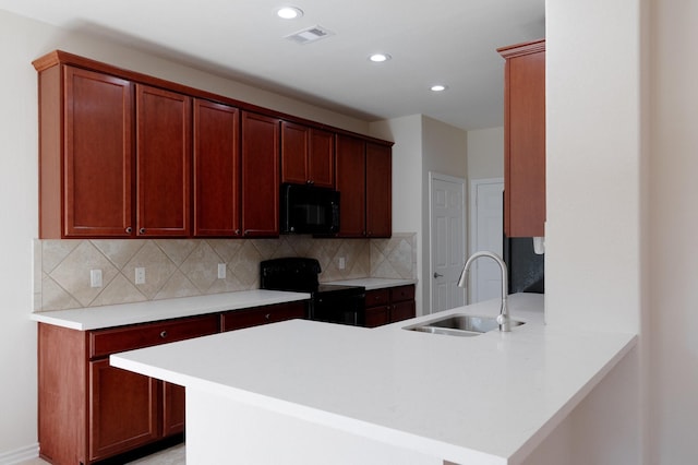 kitchen with visible vents, backsplash, a peninsula, black appliances, and a sink