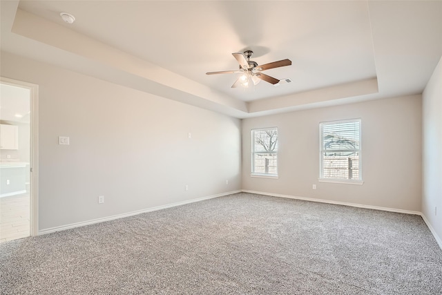 unfurnished room with ceiling fan, a raised ceiling, and carpet floors