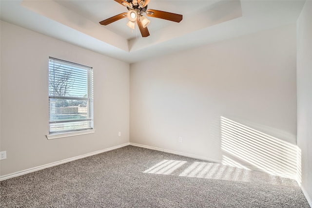 unfurnished room with ceiling fan, a raised ceiling, and carpet floors