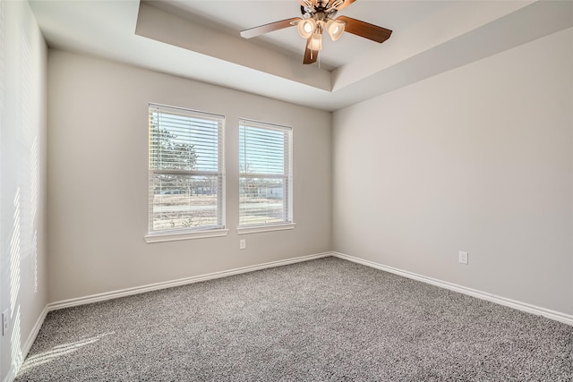 carpeted spare room with ceiling fan and a raised ceiling