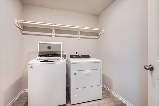 clothes washing area with light hardwood / wood-style flooring and washer and dryer