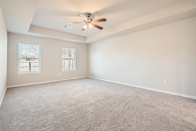 empty room with carpet floors, ceiling fan, and a tray ceiling