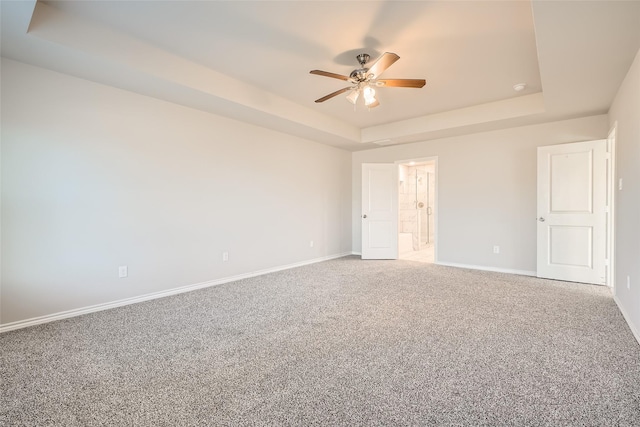 unfurnished bedroom with ensuite bathroom, a raised ceiling, ceiling fan, and carpet flooring