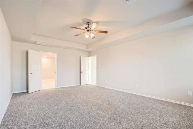 unfurnished bedroom featuring ceiling fan, light colored carpet, and a raised ceiling