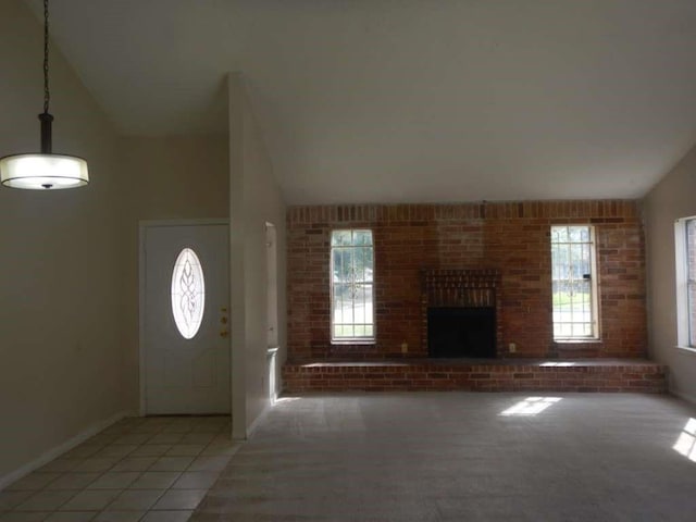 foyer entrance with a fireplace, light tile patterned flooring, vaulted ceiling, and plenty of natural light