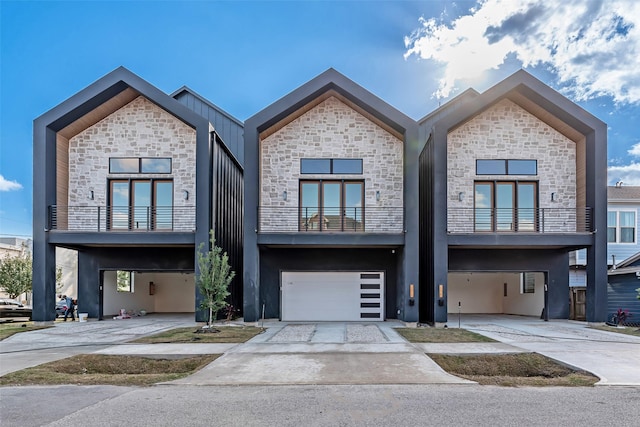 contemporary home featuring an attached garage, stone siding, and concrete driveway