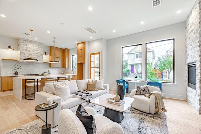 living area with recessed lighting, visible vents, and light wood finished floors