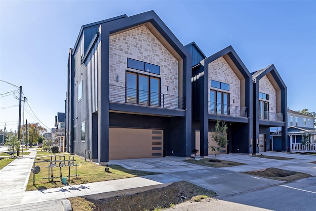 view of front of home featuring a garage, stone siding, and concrete driveway