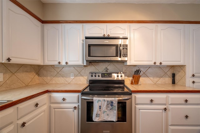 kitchen featuring decorative backsplash, tile counters, stainless steel appliances, and white cabinets