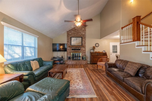 living room featuring a brick fireplace, dark wood-type flooring, high vaulted ceiling, and ceiling fan