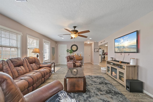 living room featuring a textured ceiling, ceiling fan, and light hardwood / wood-style flooring