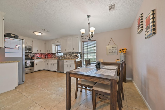 dining area featuring sink, light tile patterned floors, a textured ceiling, and an inviting chandelier