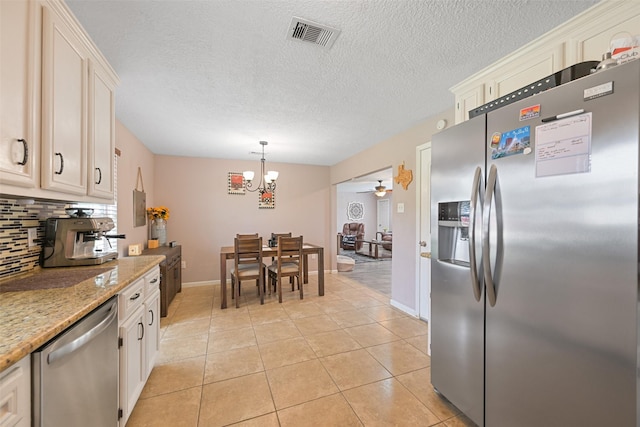 kitchen featuring light tile patterned flooring, decorative light fixtures, backsplash, light stone counters, and stainless steel appliances