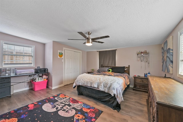 bedroom with hardwood / wood-style flooring, a textured ceiling, a closet, and ceiling fan