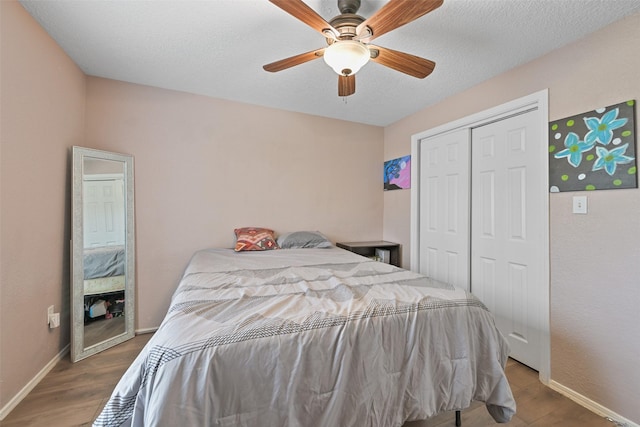 bedroom with hardwood / wood-style flooring, ceiling fan, a closet, and a textured ceiling