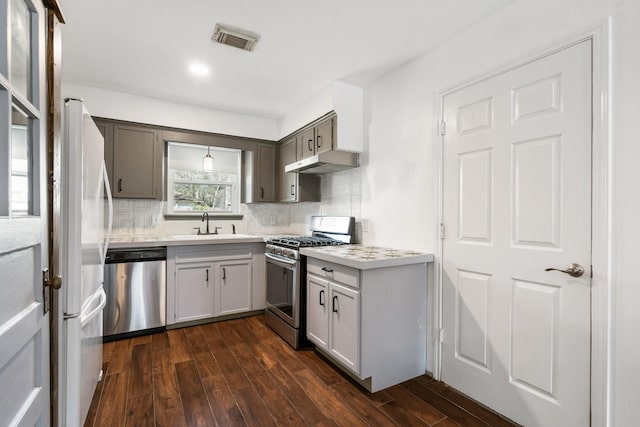 kitchen featuring sink, gray cabinets, tasteful backsplash, appliances with stainless steel finishes, and dark hardwood / wood-style floors