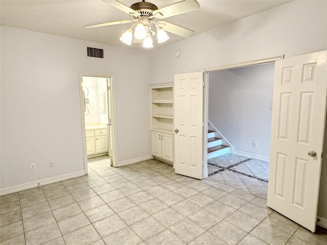 unfurnished bedroom featuring visible vents, baseboards, a ceiling fan, ensuite bathroom, and light tile patterned flooring