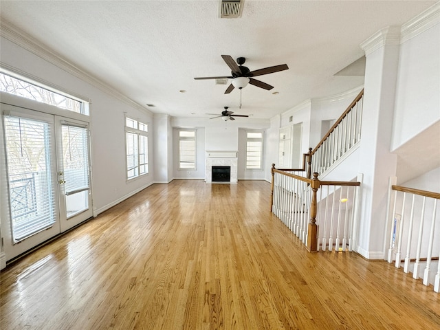 unfurnished living room featuring a wealth of natural light, light wood-style floors, and ornamental molding