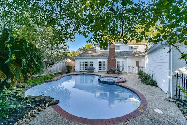 view of swimming pool featuring an in ground hot tub, a patio area, and french doors