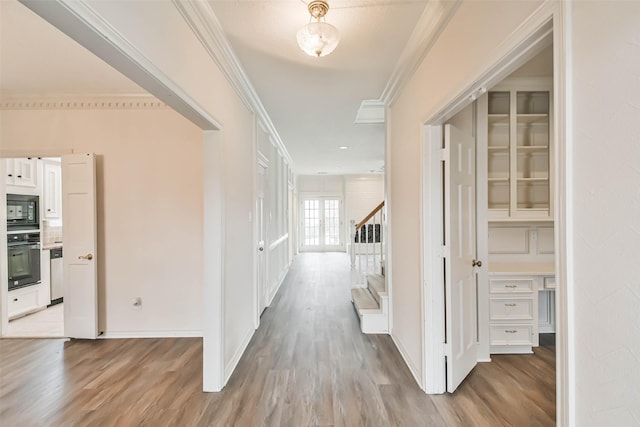 corridor with ornamental molding and light hardwood / wood-style floors