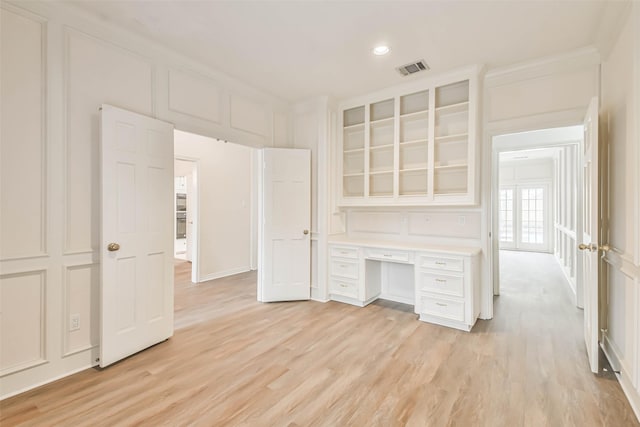 interior space featuring crown molding, built in desk, and light wood-type flooring