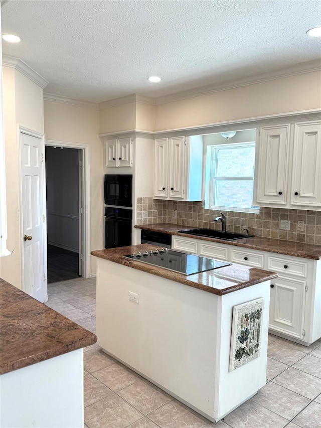 kitchen with black appliances, sink, a kitchen island, and white cabinets