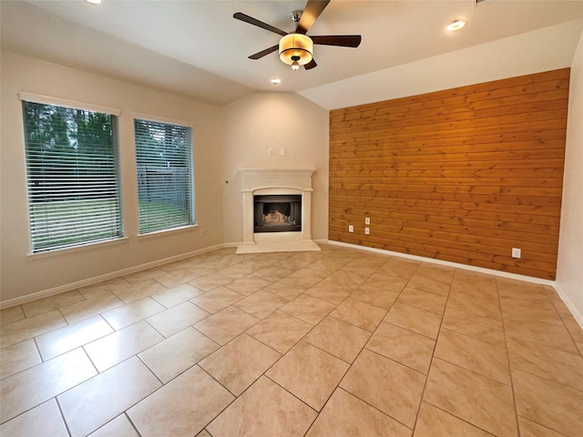 unfurnished living room with vaulted ceiling, a fireplace with raised hearth, light tile patterned floors, and wood walls