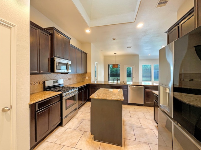 kitchen with visible vents, appliances with stainless steel finishes, a center island, a peninsula, and decorative light fixtures