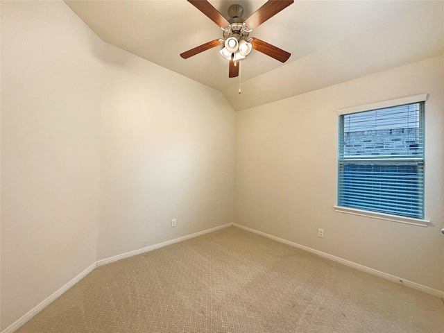 empty room with lofted ceiling, carpet floors, ceiling fan, and baseboards