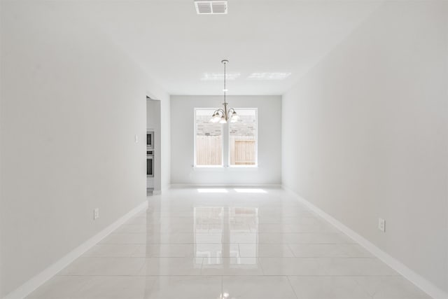 spare room with a chandelier and light tile patterned flooring