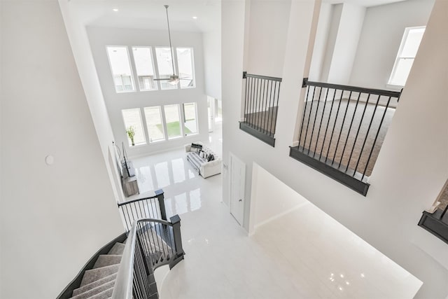 stairs with ceiling fan and a towering ceiling