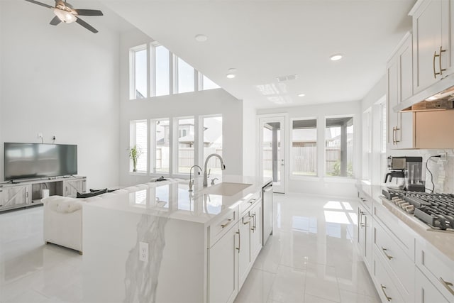 kitchen featuring white cabinetry, sink, stainless steel appliances, and a center island with sink